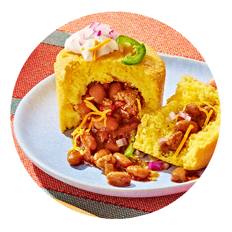 Chili cornbread pie on a plate, broken open, with chili beans spilling out